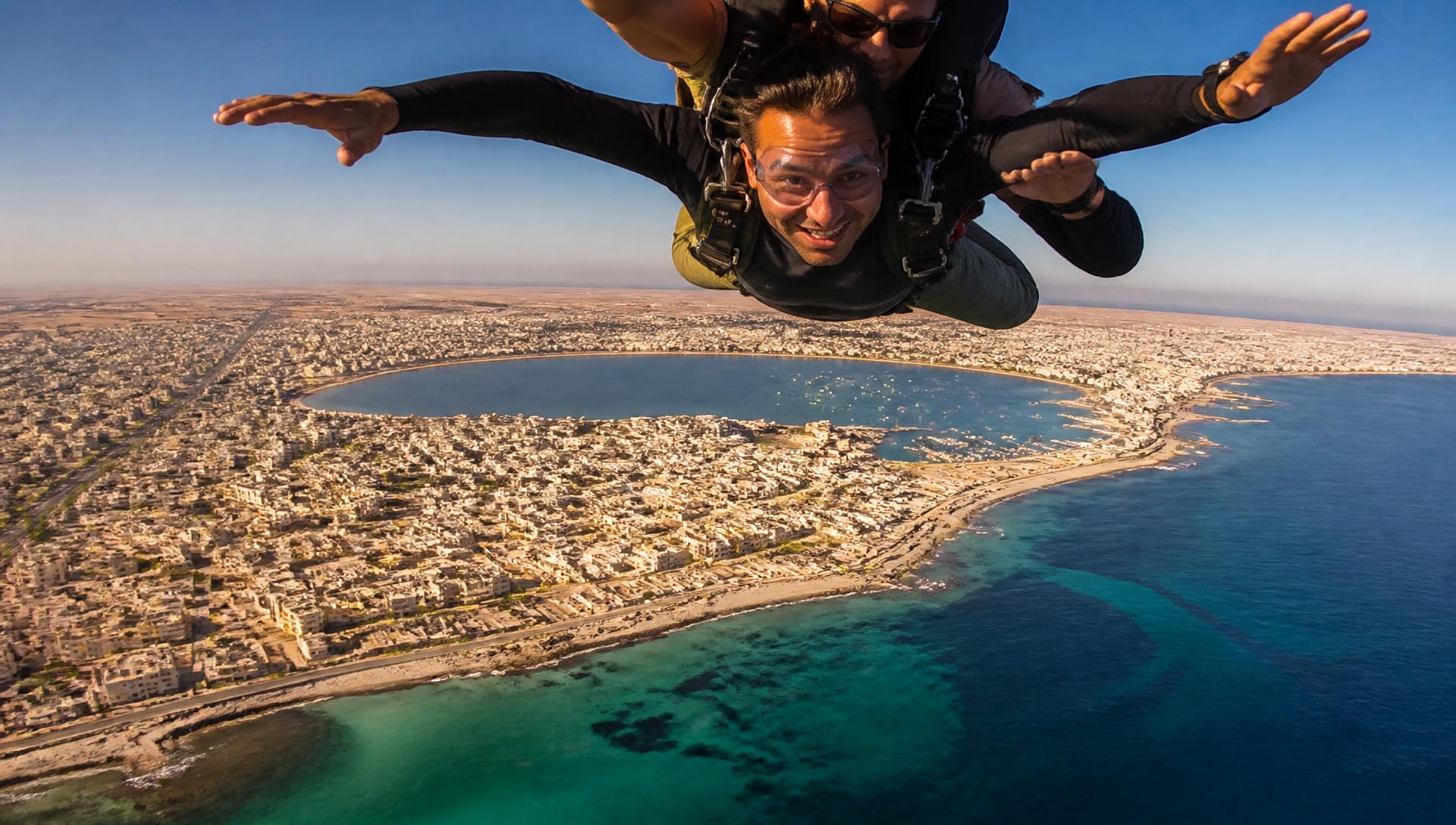 Tandem skydiver in freefall above the city of Benghazi and its lagoon